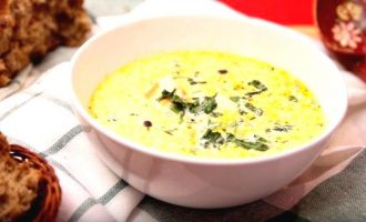 Подача сырного супа с белой тарелке с зеленью