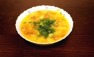 Готовый суп в белой тарелке с зеленью