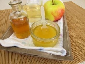 На столе пиала с медом, яблоко и укус